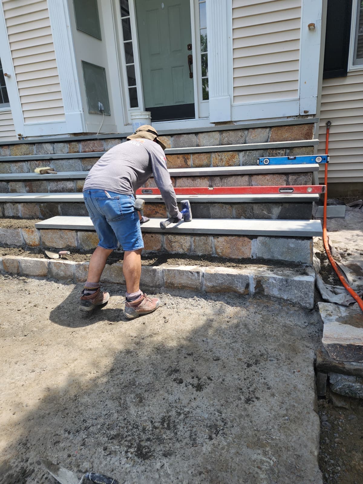 Granite steps installation — Connecticut Granite block steps being leveled during a front entrance installation