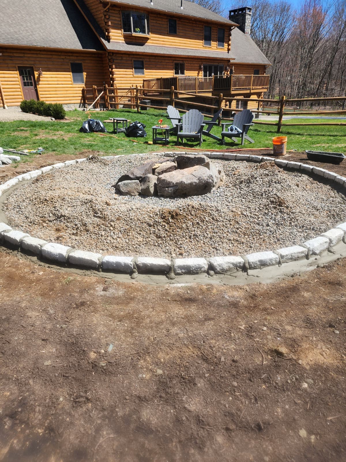 Stone fire pit with Belgian block ring — Connecticut Circular stone fire pit ringed with Belgian block in a backyard